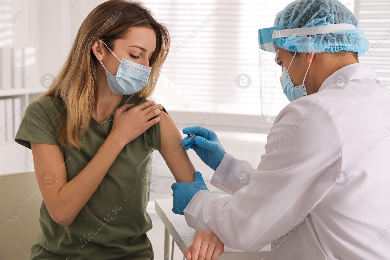 Photo of Doctor vaccinating young woman against Covid-19 in clinic