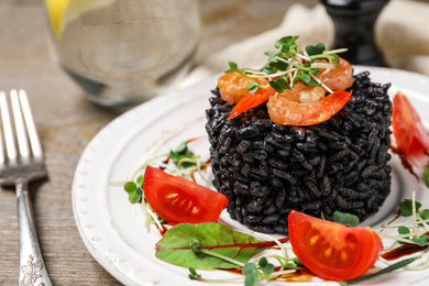 Delicious black risotto with seafood served on plate, closeup