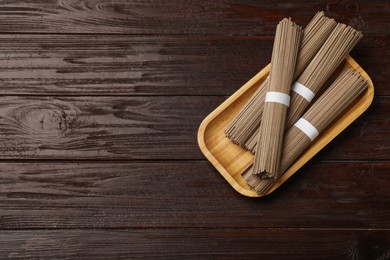 Uncooked buckwheat noodles (soba) on wooden table, top view. Space for text