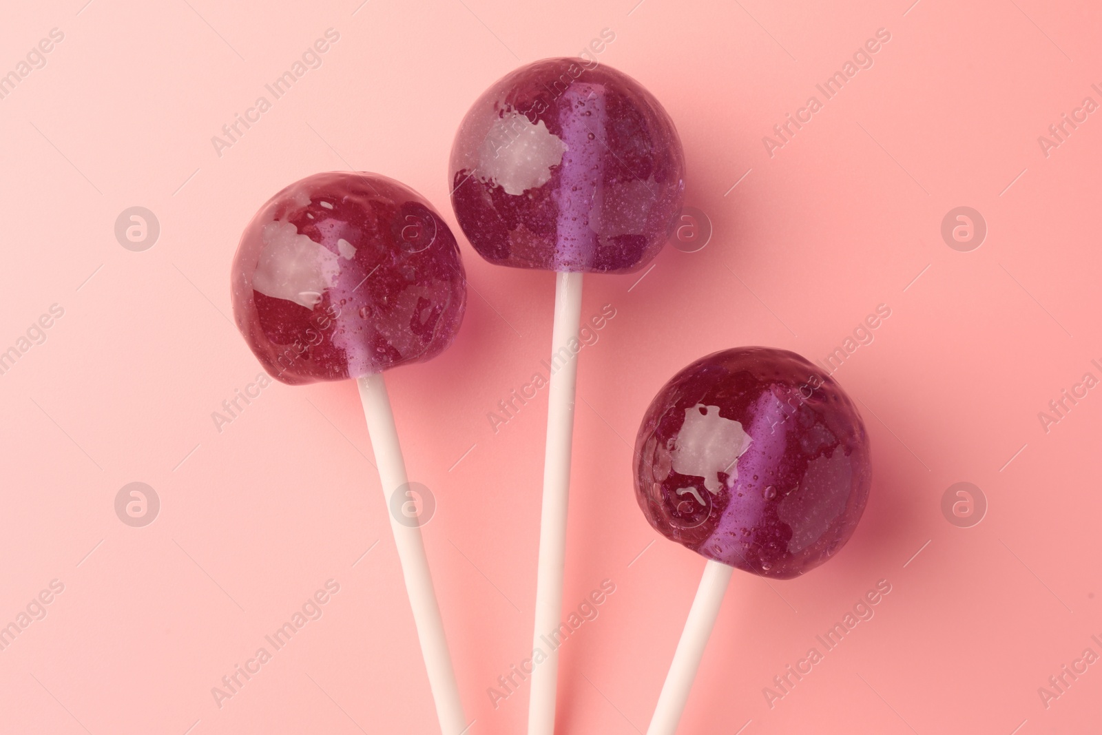 Photo of Tasty lollipops on pink background, flat lay