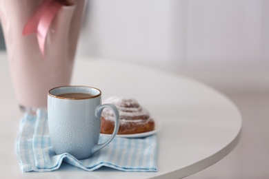 Photo of Cup of coffee and tasty bun on table