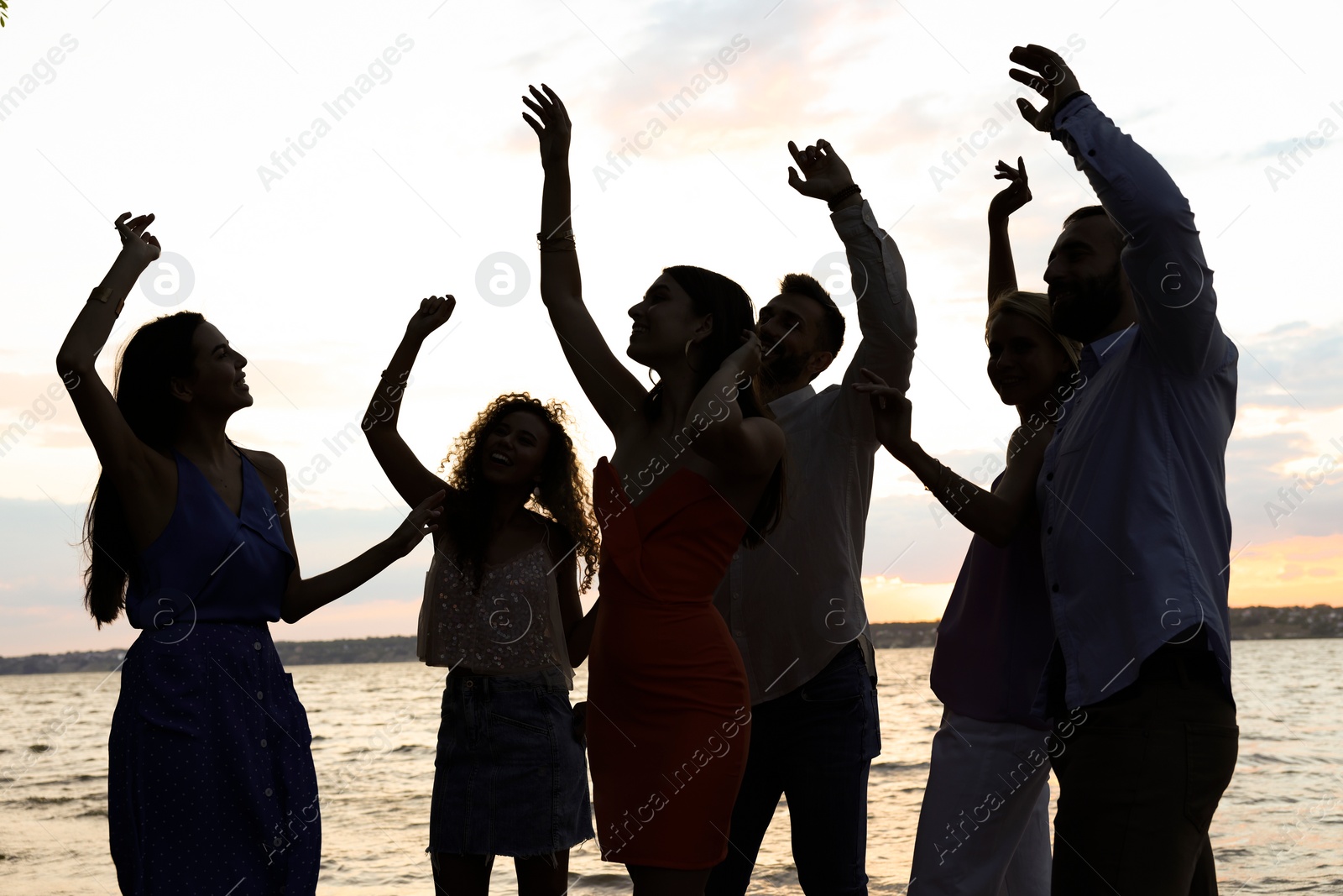 Image of Friends dancing outdoors. Silhouettes of people near river