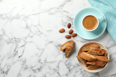 Flat lay composition with tasty cantucci and aromatic coffee on white marble table, space for text. Traditional Italian almond biscuits