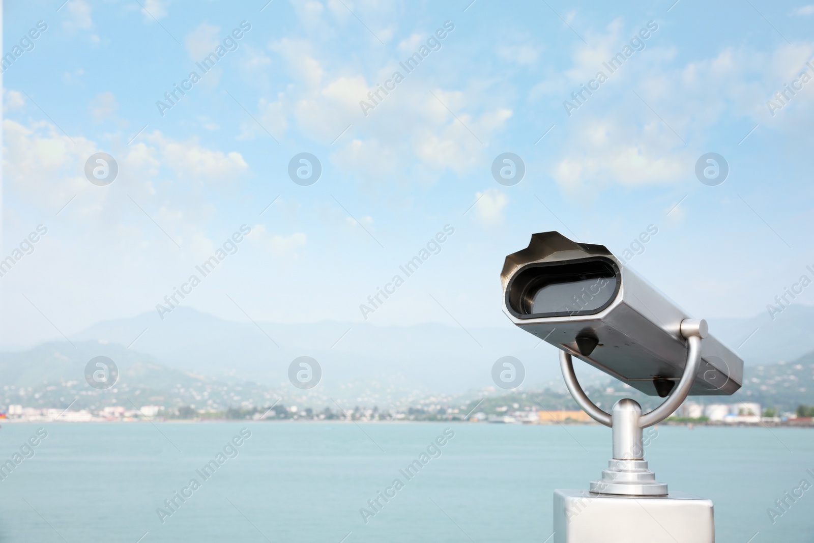 Photo of Metal tower viewer installed near sea, space for text. Mounted binoculars