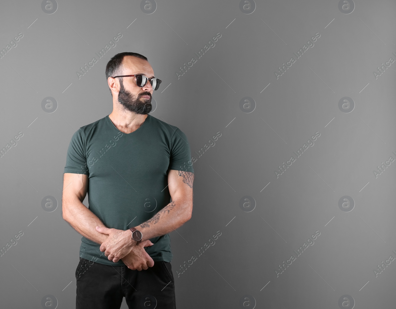 Photo of Portrait of handsome tattooed man on grey background. Space for text