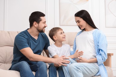 Photo of Pregnant woman spending time with her son and husband at home. Happy family