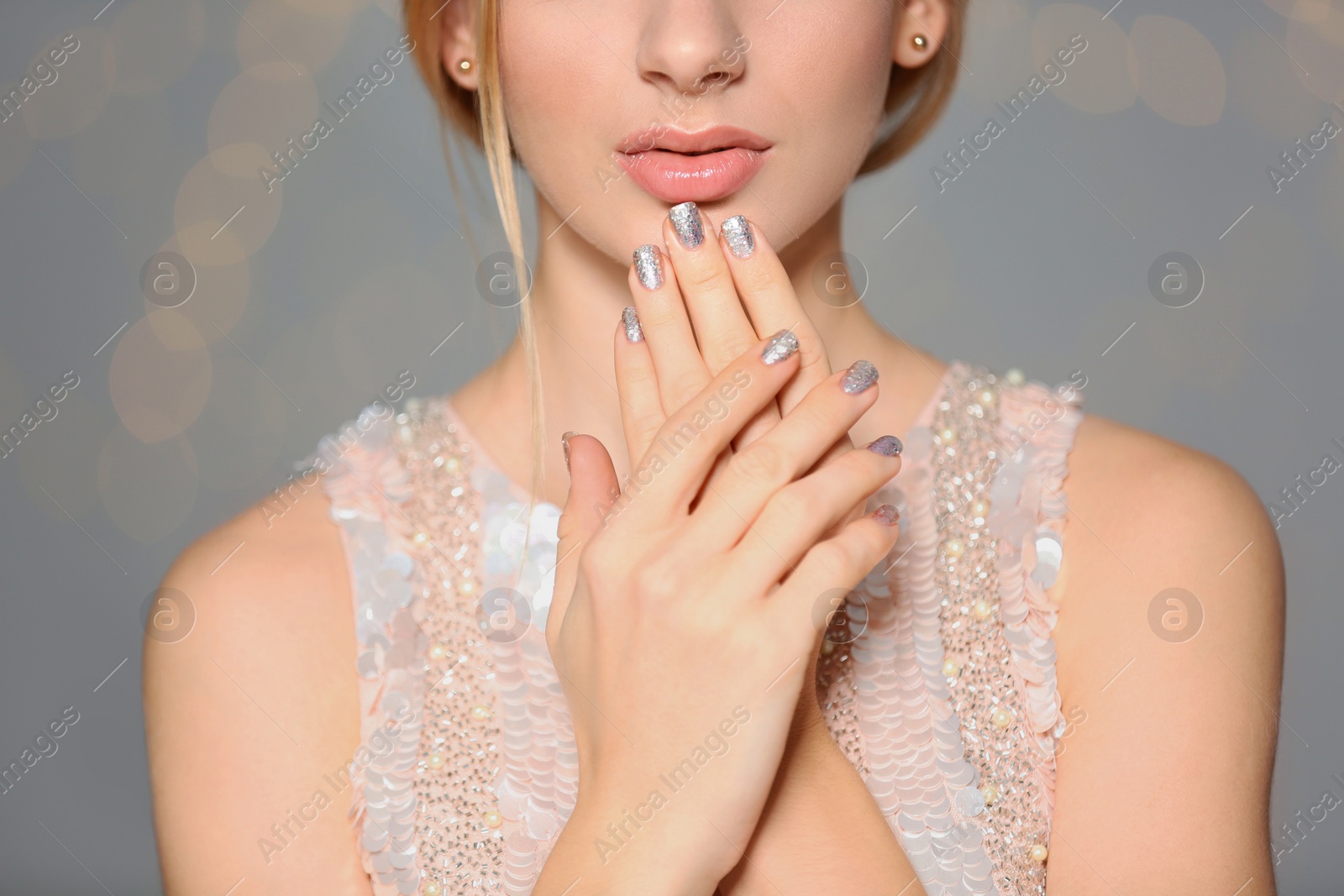 Photo of Beautiful young woman with shiny manicure on blurred background, closeup. Nail polish trends