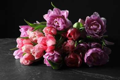 Photo of Beautiful bouquet of colorful tulip flowers on black table