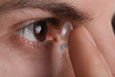 Closeup view of man putting contact lens in his eye