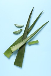 Photo of Cut aloe vera leaves on light blue background, flat lay