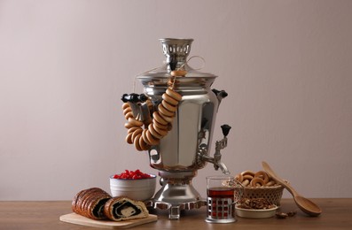 Photo of Traditional Russian samovar with treats on wooden table