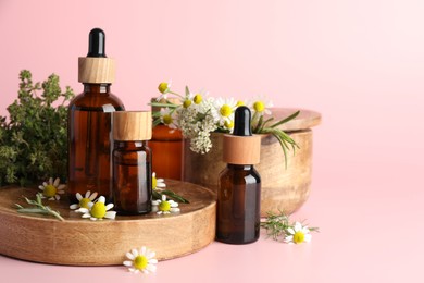 Photo of Aromatherapy. Different essential oils and flowers on pink background