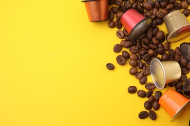 Many coffee capsules and beans on yellow background, above view. Space for text