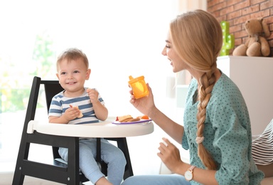 Photo of Woman feeding her child in highchair at home. Healthy baby food