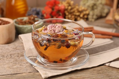 Photo of Aromatic tea with different dry herbs and flowers on wooden table, closeup