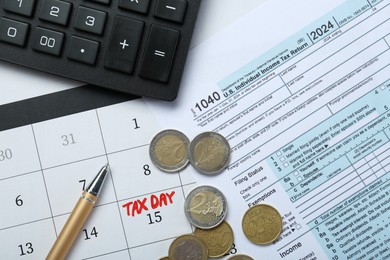 Calendar with date reminder about tax day, documents, coins, pen and calculator, top view