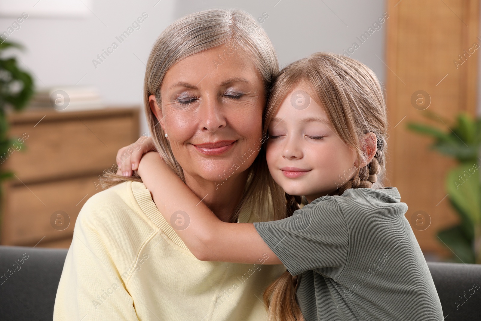 Photo of Happy grandmother hugging her granddaughter at home