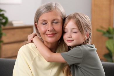 Happy grandmother hugging her granddaughter at home