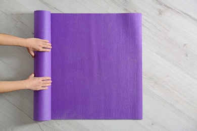 Photo of Woman rolling yoga mat on floor, top view. Space for text