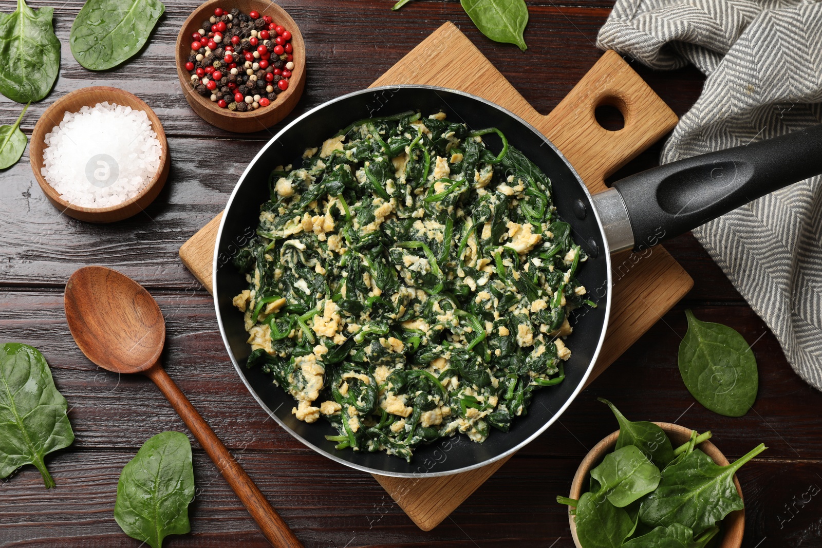 Photo of Tasty spinach dip with eggs in dish served on wooden table, flat lay