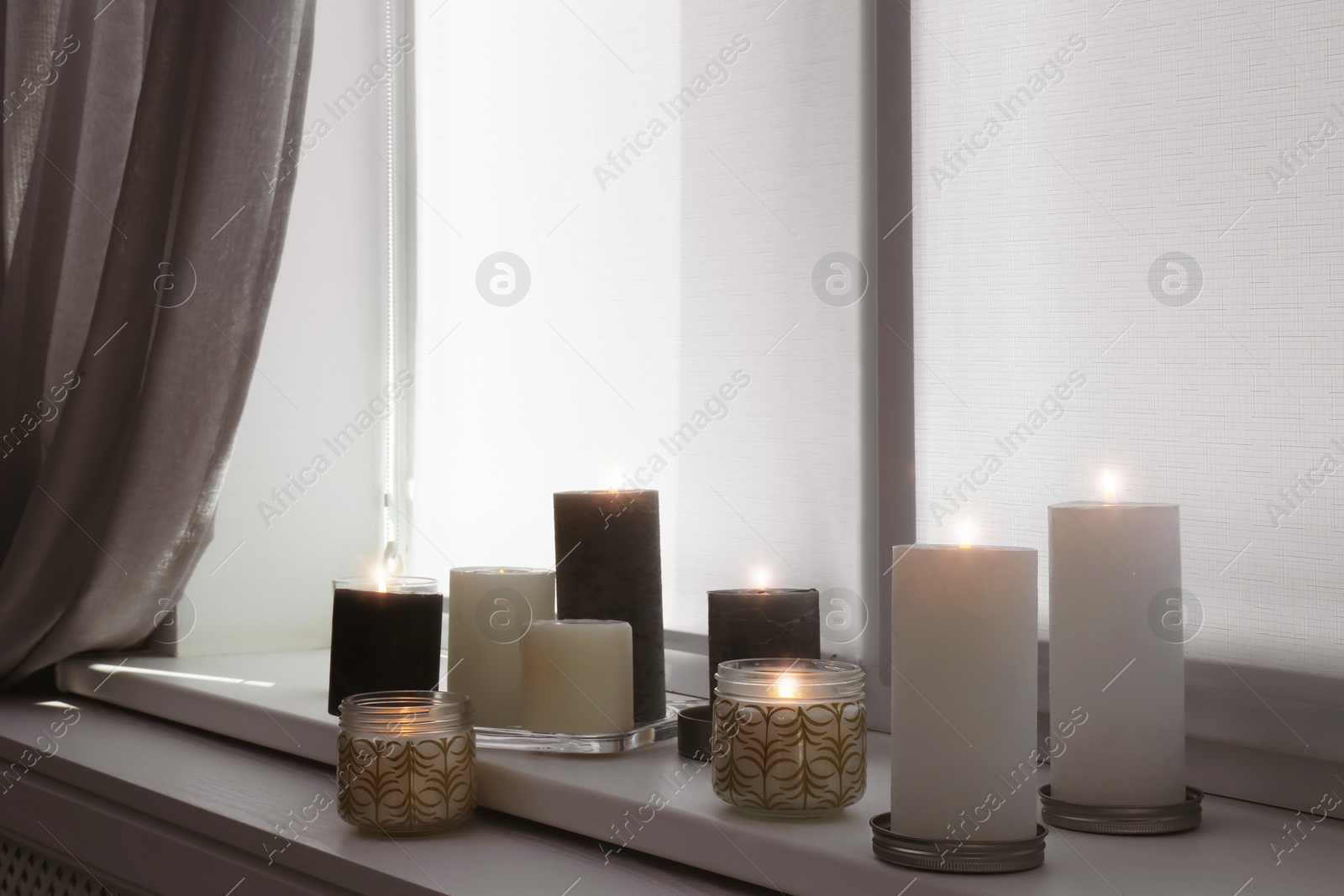 Photo of Burning candles on window sill in room