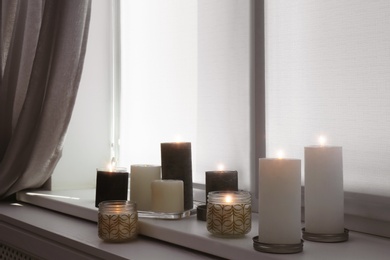 Photo of Burning candles on window sill in room