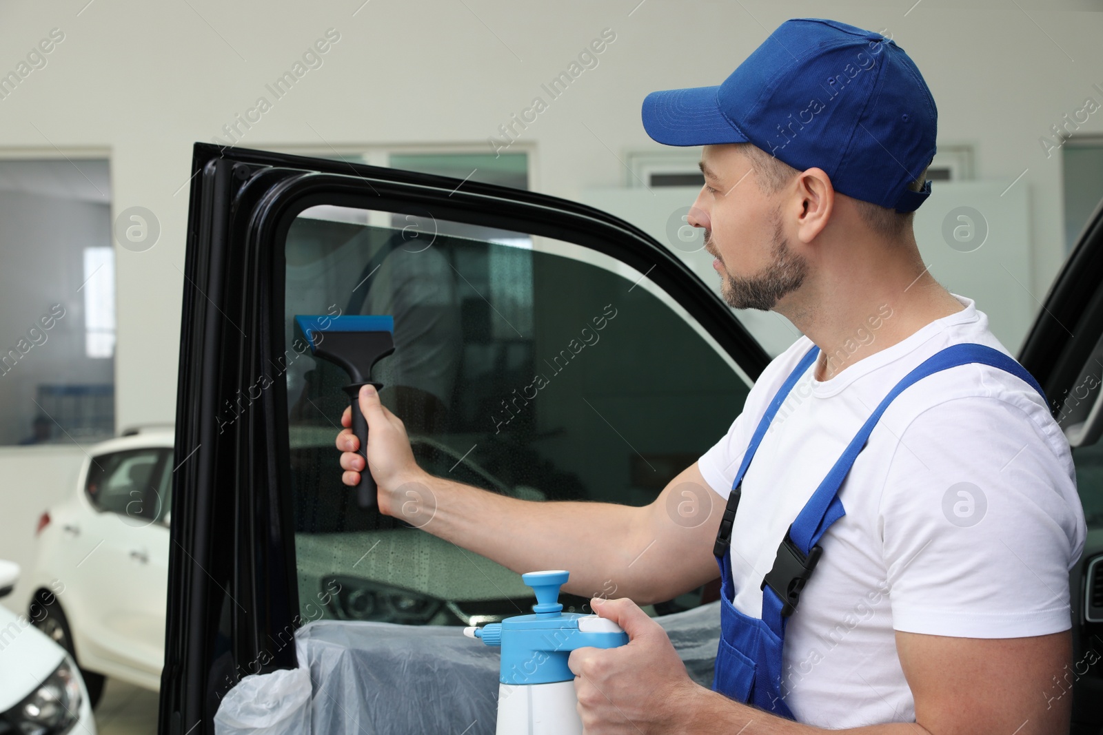 Photo of Worker washing tinted car window in workshop