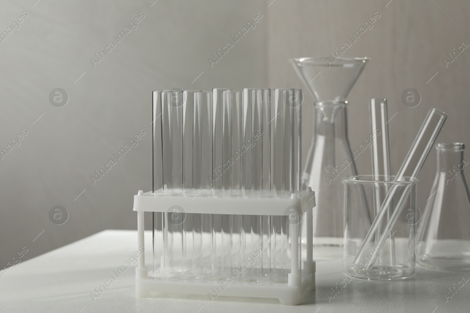 Photo of Set of laboratory glassware on white table against grey background