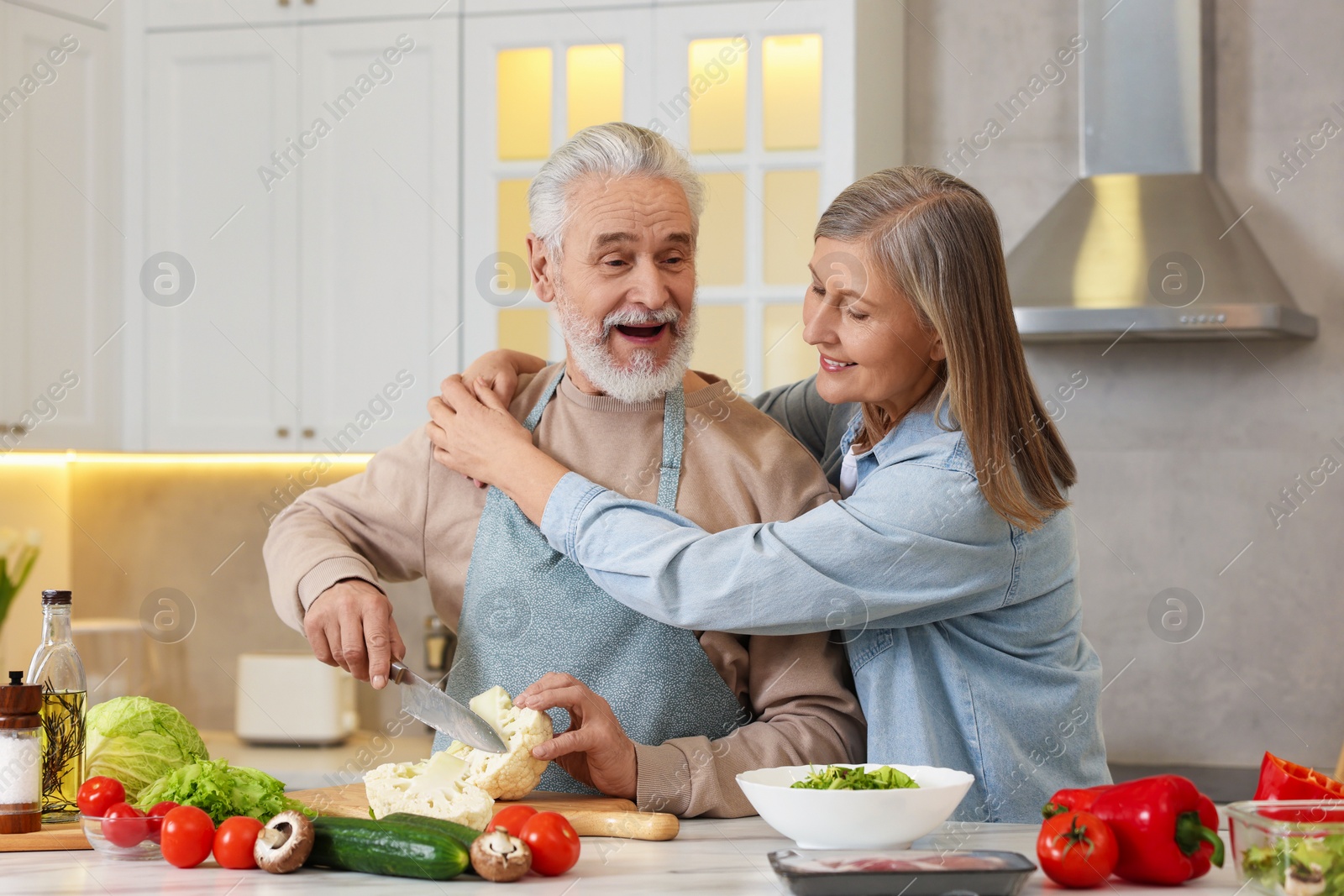 Photo of Happy senior couple cooking together in kitchen