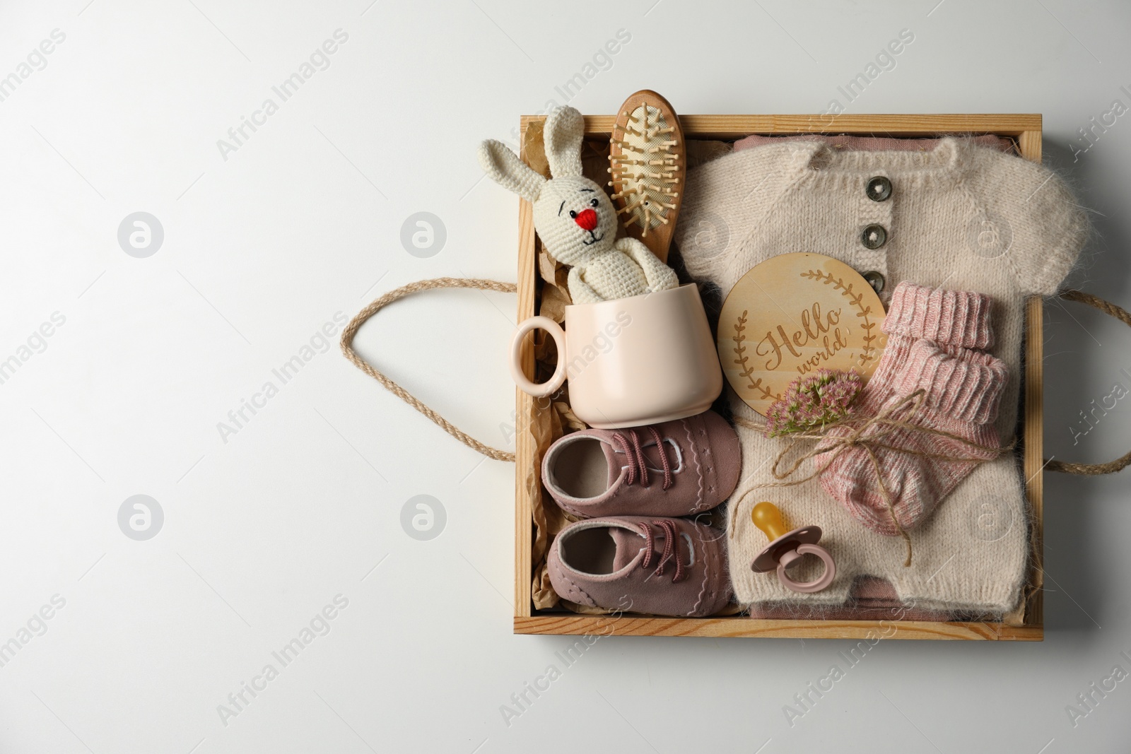 Photo of Box with baby clothes, shoes and accessories on light background, top view. Space for text