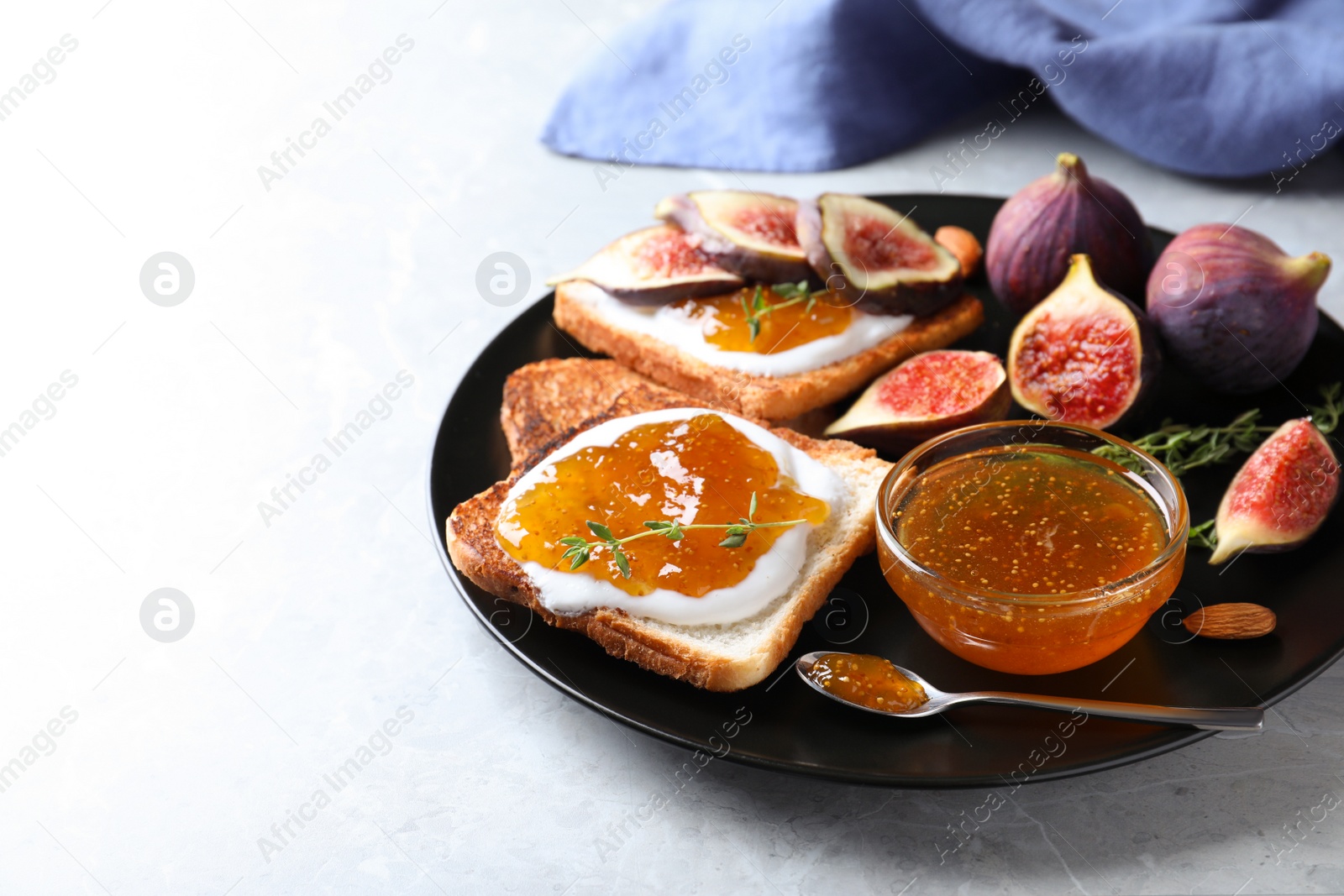 Photo of Tasty toasts with fig jam and cream cheese on grey marble table, closeup