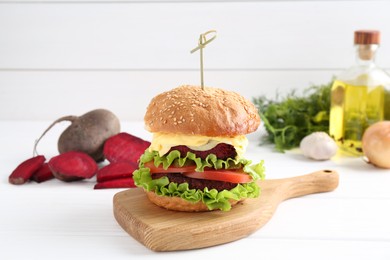 Delicious vegetarian burger and ingredients on white wooden table