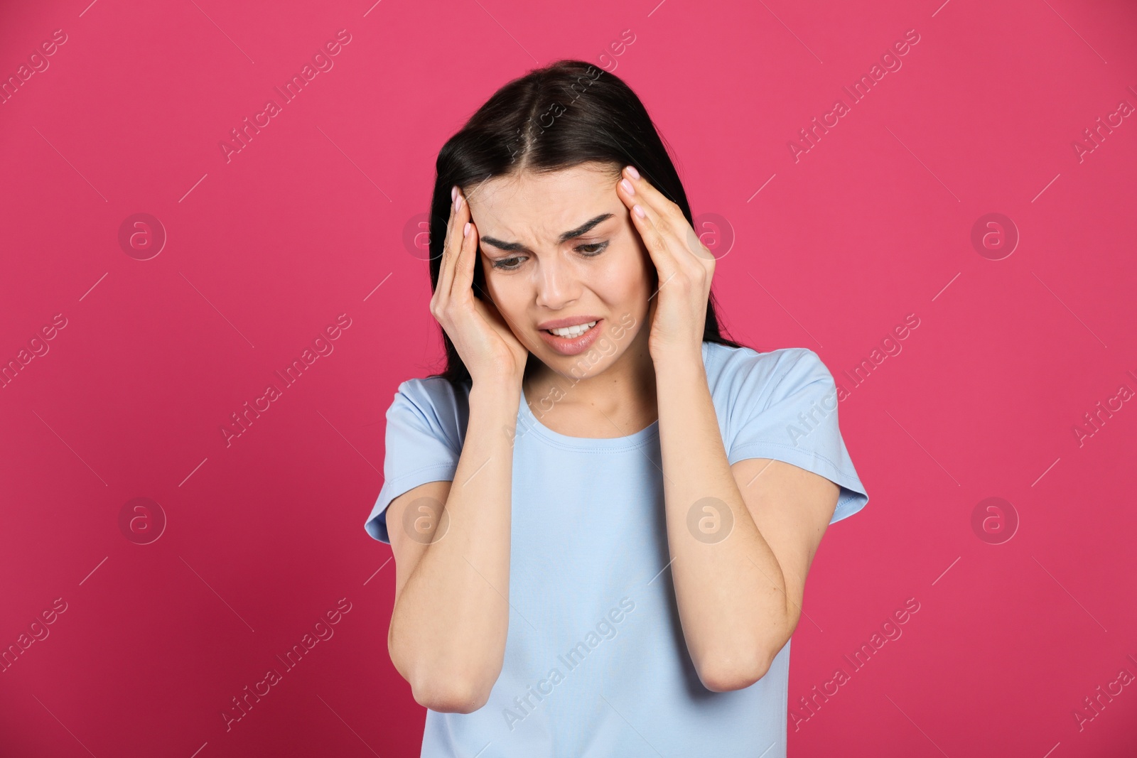 Photo of Woman suffering from migraine on pink background