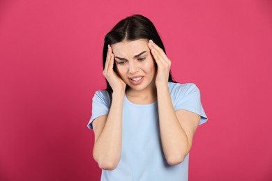 Photo of Woman suffering from migraine on pink background