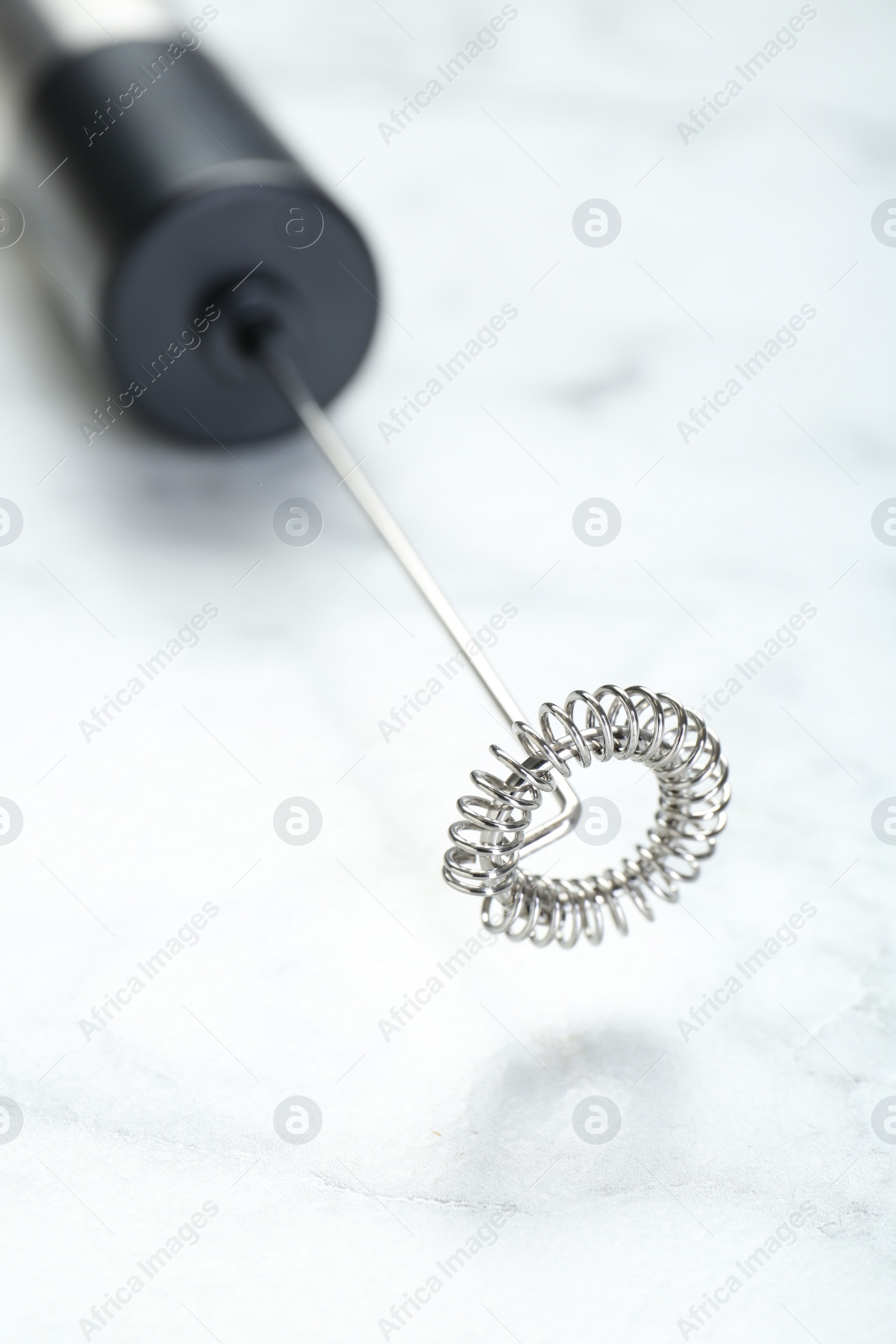 Photo of Black milk frother wand on white marble table, closeup