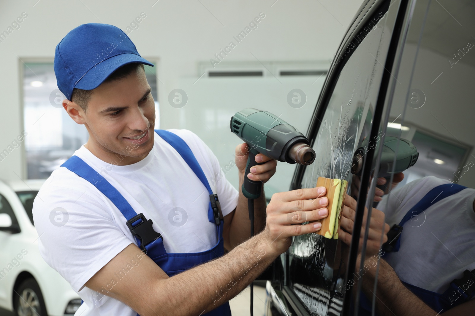 Photo of Worker tinting car window with foil in workshop