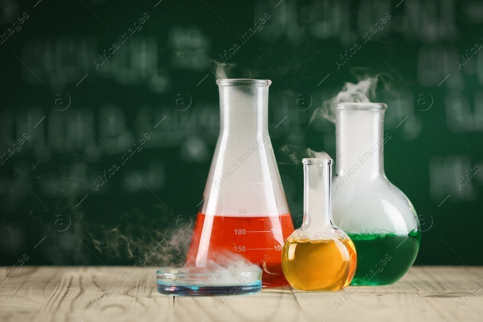 Photo of Laboratory glassware with colorful liquids on wooden table, space for text. Chemical reaction