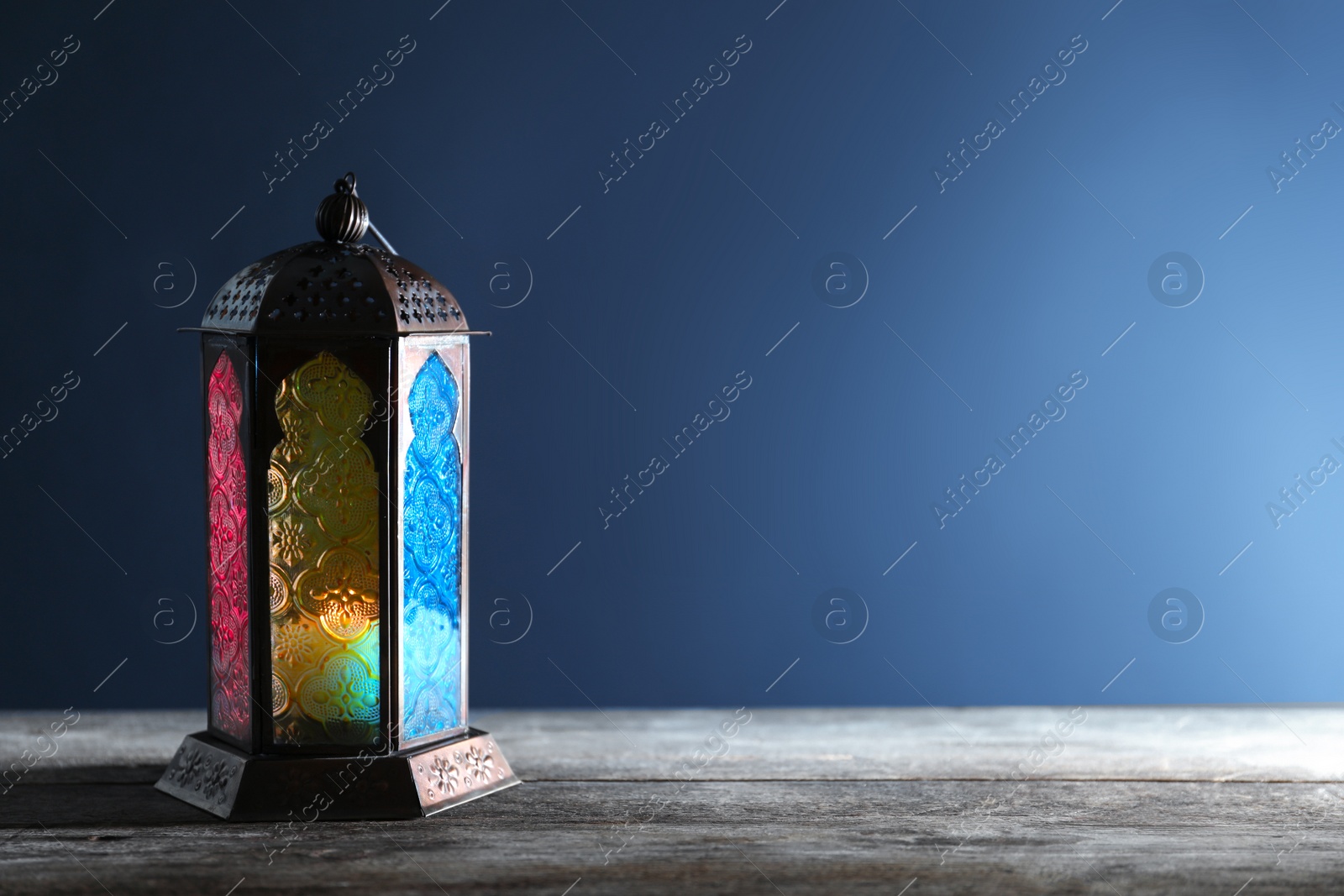 Photo of Muslim lamp with candle on wooden table. Fanous as Ramadan symbol