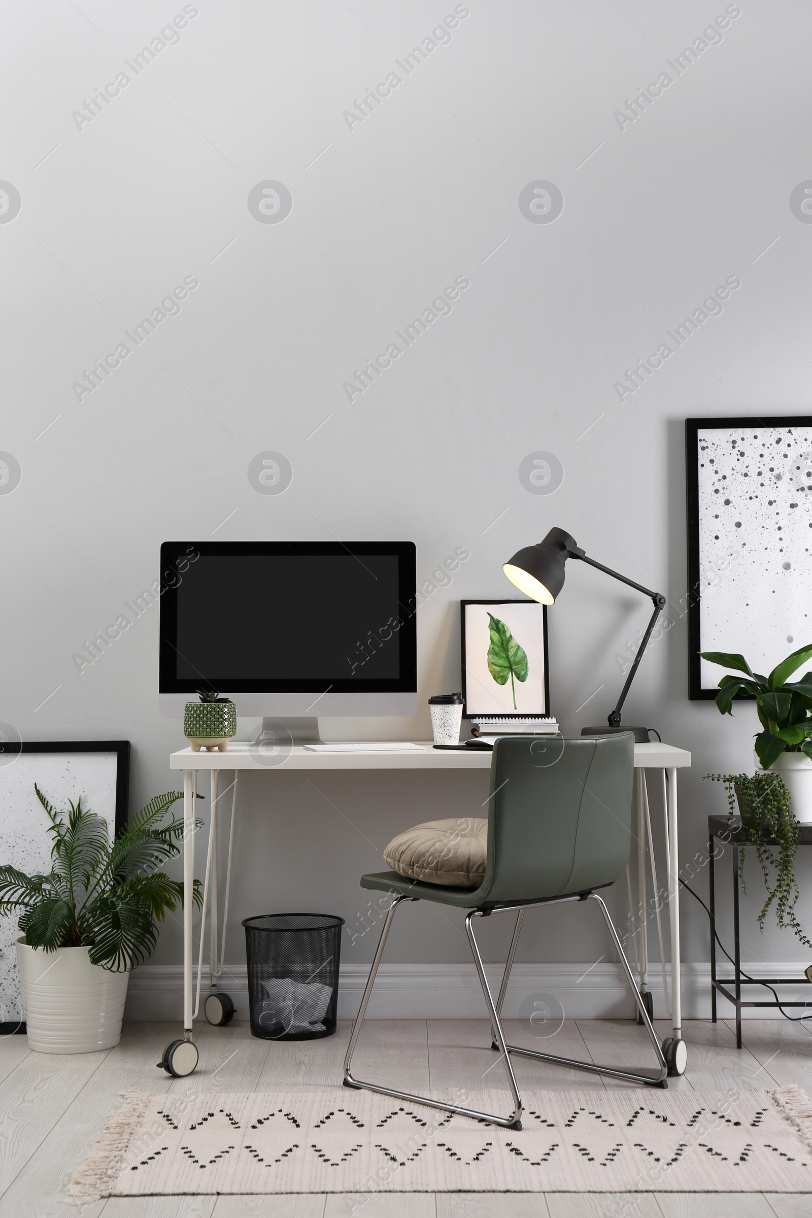 Photo of Comfortable workplace with modern computer and houseplants in room. Interior design