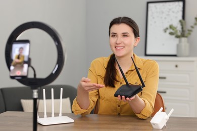 Smiling technology blogger recording video review about WI-FI devices at home