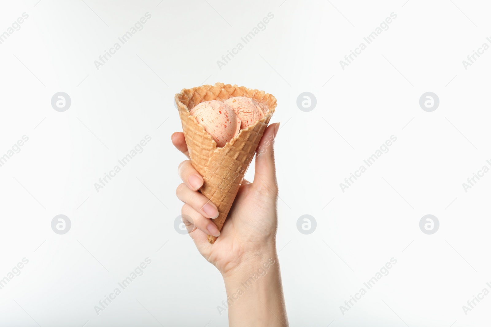 Photo of Woman holding delicious ice cream in waffle cone on white background, closeup