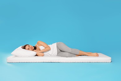 Photo of Young woman sleeping on soft mattress against light blue background