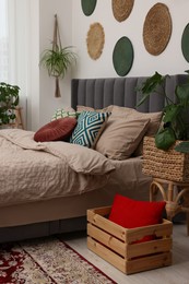 Photo of Large comfortable bed and potted houseplants in stylish bedroom. Interior design