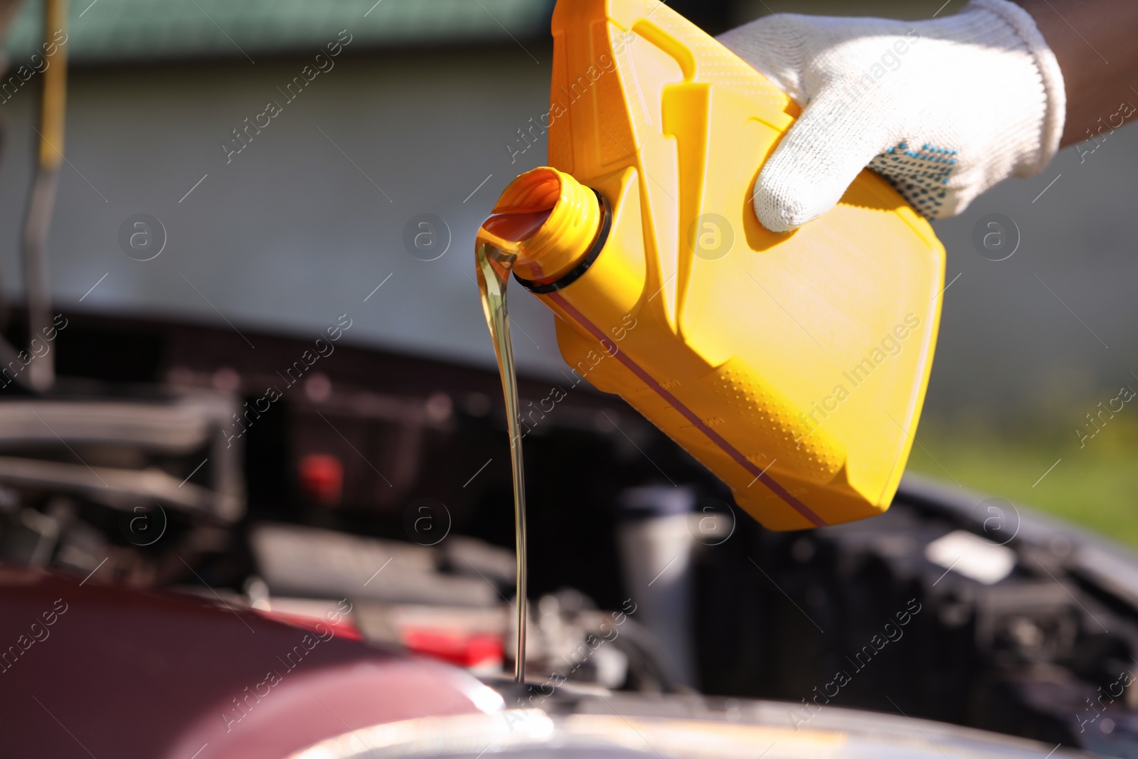 Photo of Man pouring motor oil from yellow container, closeup