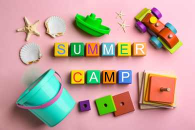 Colorful wooden cubes with phrase SUMMER CAMP on pink background, flat lay