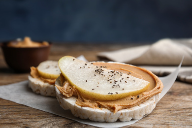 Photo of Puffed rice cakes with peanut butter and pear on wooden table