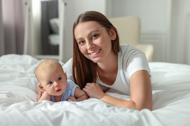 Photo of Mother with her cute baby on bed indoors