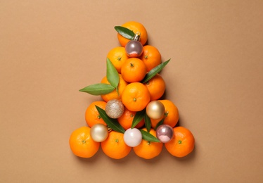 Photo of Christmas tree shape made of tangerines on light brown background, flat lay