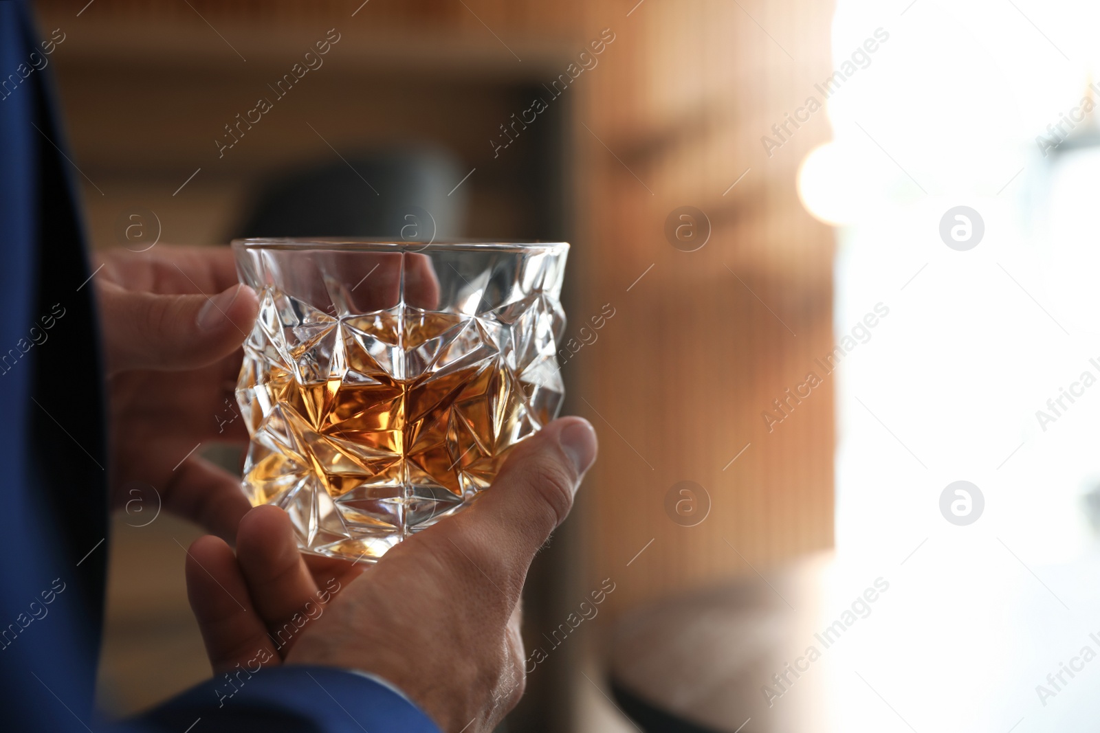 Photo of Young man with glass of whiskey indoors, closeup view. Space for text