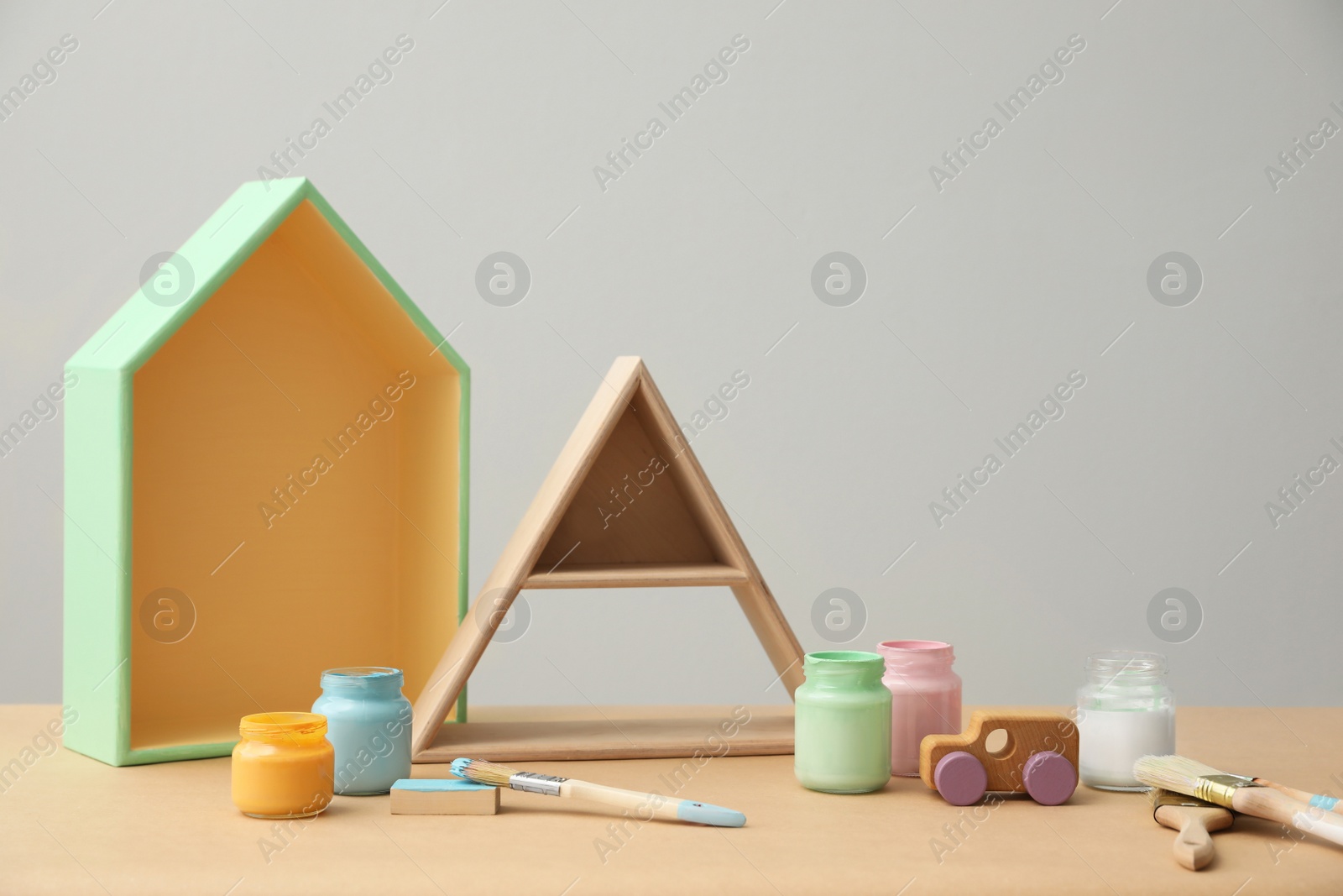 Photo of Composition with jars of paints and shelves on wooden table. Interior elements